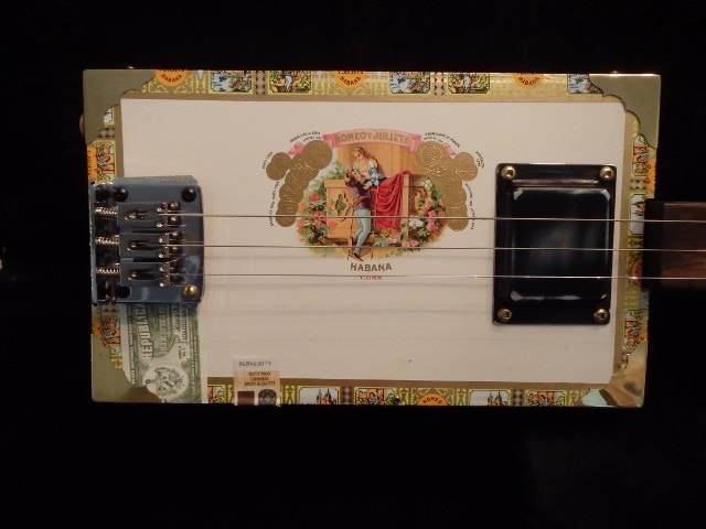 Turquoise cigar box guitar with red amplifier.
