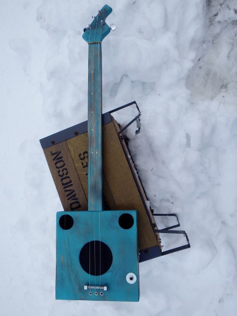 Turquoise cigar box guitar in the snow