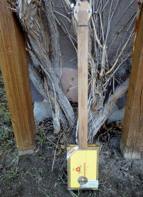 Montecristo yellow cigar box guitar against vine.